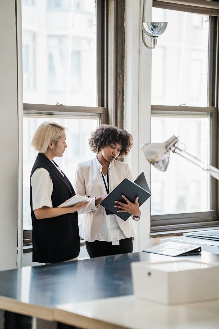 Two businesswomen reviewing documents in a bright office setting.